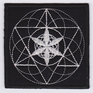 May include: A black embroidered patch with a white geometric design. The design features a circle with a star inside, surrounded by a series of overlapping triangles and circles.