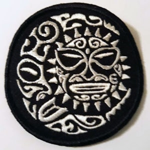May include: White embroidered tribal mask design on a black oval patch.