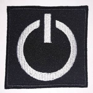 May include: Black fabric patch with a white embroidered power button symbol.