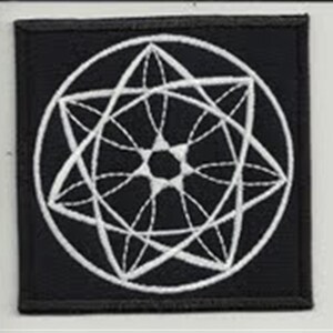 May include: A black fabric patch with a white embroidered geometric design. The design is a circle with a star-like pattern inside.