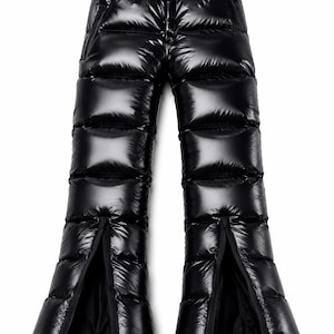 Op de afbeelding: Zwarte broek met hoge taille, een glanzende afwerking en horizontale gewatteerde banen. De broek is voorzien van een geïntegreerde zwarte kunststof gespriem in de taille en verticale ritssluitingen aan de onderkant van elke broekspijp.