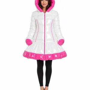 Può includere: Un piumino bianco lucido con fodera del cappuccio rosa acceso, finiture della cerniera rosa e orlo rosa. Il cappotto presenta un motivo trapuntato, una cerniera frontale a tutta lunghezza e una sezione inferiore svasata con maniche lunghe.