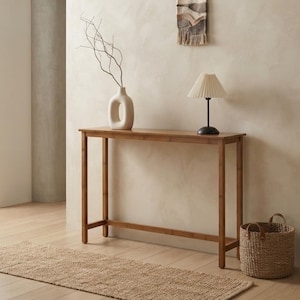 May include: A rectangular bamboo console table with four straight legs and a thin horizontal support bar near the base. The table features a natural light brown wood grain finish and a slim profile, providing a flat surface for decorative items.