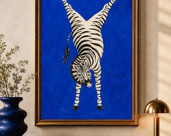 Op de afbeelding: Een ingelijst schilderij met een zebra met zwart-witte strepen in een handstandpositie tegen een effen, levendige blauwe achtergrond. De zebra is verticaal georiënteerd met de hoeven naar boven en de kop naar beneden gericht.