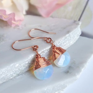 May include: A pair of copper wire wrapped earrings with iridescent opal teardrop stones.