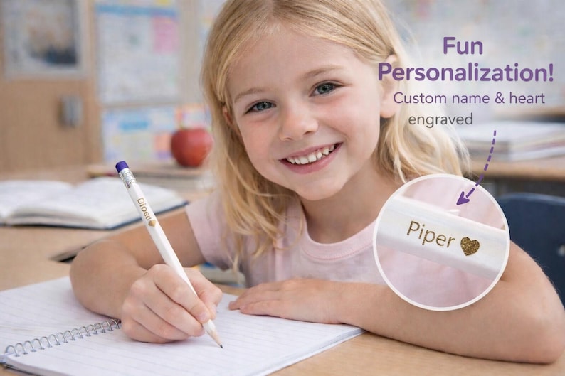 May include: A white pencil with a purple eraser and the name "Piper" and a gold heart engraved on it. The pencil is being used to write on a spiral notebook. The image also includes the text "Fun Personalization! Custom name & heart engraved."