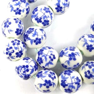 May include: A strand of white ceramic beads with a blue floral pattern. The beads are round and have a glossy finish.