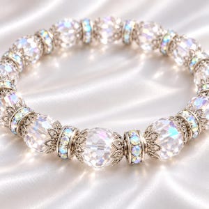Puede incluir: Una pulsera circular que presenta una alternancia de cuentas de cristal transparente facetado y espaciadores de metal plateado más pequeños. Los espaciadores están adornados con diminutos cristales iridiscentes y filigrana metálica.