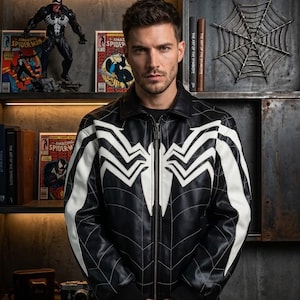 May include: A black leather jacket featuring a large white spider emblem on the chest and shoulders, with thin white web-like lines across the front, a standard collar, a full-length front zipper, and black ribbed cuffs at the wrists.