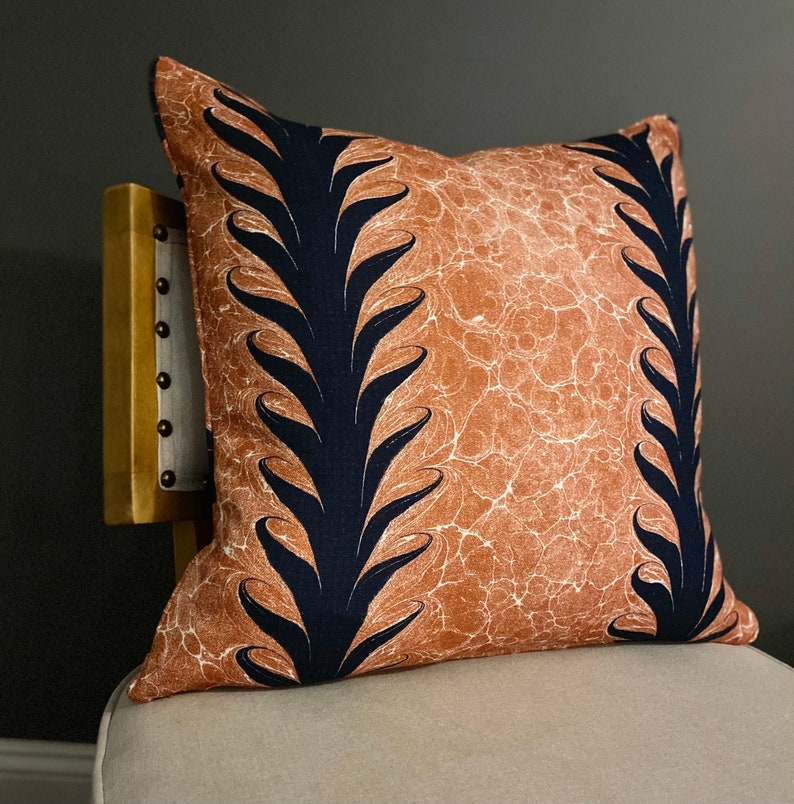 Może przedstawiać: Dekoracyjna poduszka z brązowym tłem i czarnym wzorem kwiatowym. Poduszka wykonana jest z miękkiej, fakturowanej tkaniny.