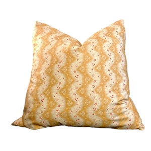 May include: A yellow and white patterned throw pillow with a red floral design. The pillow is made of a soft, comfortable fabric and has a square shape.
