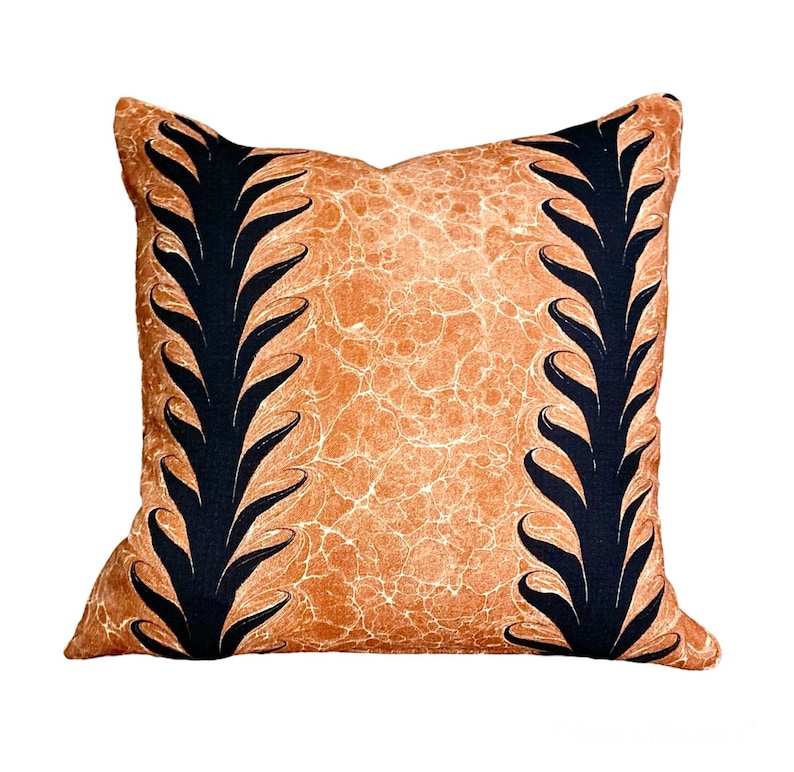 Może przedstawiać: Dekoracyjna poduszka z brązowym tłem i czarnymi wzorami w kształcie liści po bokach.