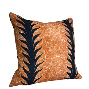 Może przedstawiać: Brązowa poduszka dekoracyjna z czarnym wzorem liści. Poduszka ma fakturowaną powierzchnię.