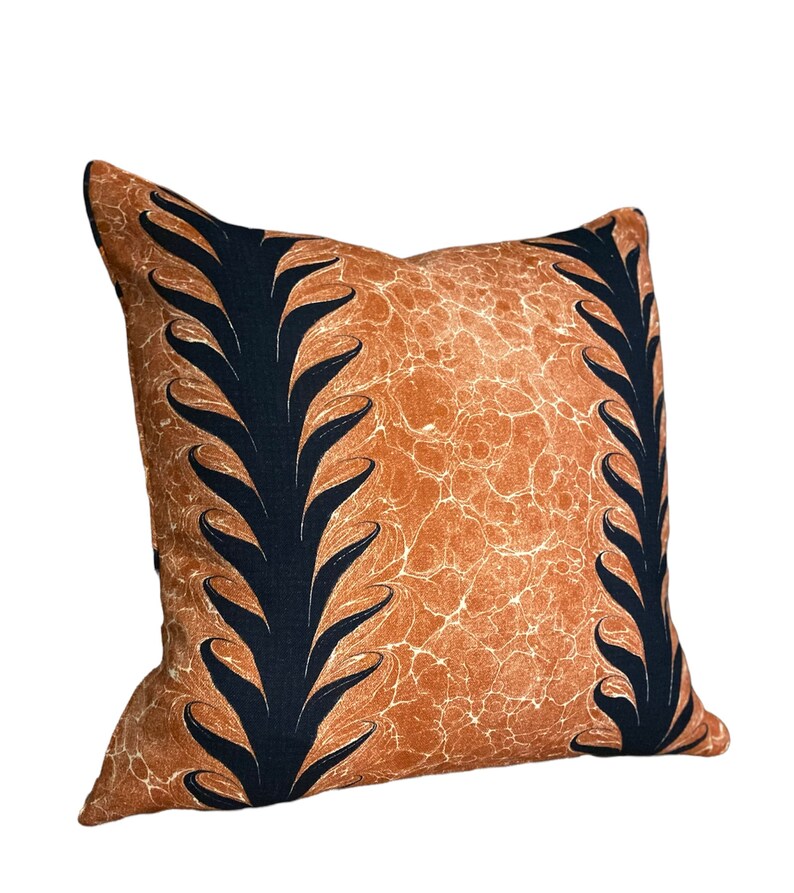 Może przedstawiać: Brązowa poduszka dekoracyjna z czarnym wzorem liści. Poduszka ma fakturowaną powierzchnię.
