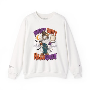 May include: A white long-sleeve sweatshirt featuring a graphic of a ghost wearing glasses, a crown, and scrubs, holding a coffee cup and clipboard. The text reads NIGHT SHIFT HALLOQUEEN, surrounded by a crescent moon, clock, bats, and a heartbeat line.