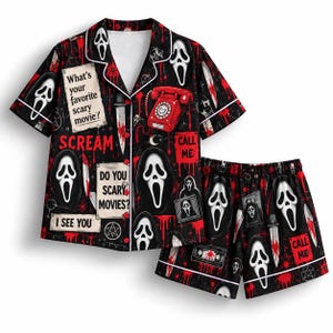 Puede incluir: Un conjunto de pijama negro que incluye una camisa de manga corta con botones y pantalones cortos a juego. La tela presenta un estampado repetitivo de máscaras fantasmales blancas, teléfonos rojos, cuchillos y texto como "What's your favorite scary movie?"