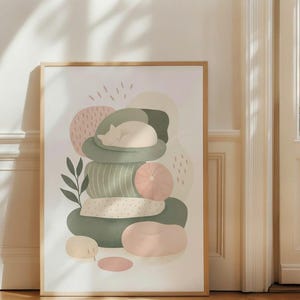 Peut inclure: Une affiche murale verticale encadrée représentant une illustration stylisée d'un chat endormi reposant sur une pile de coussins de formes variées dans des tons vert sauge, rose poudré et crème, agrémentée de motifs de feuilles et de traits.