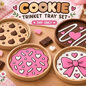 May include: A set of four round trinket trays featuring biscuit-themed designs including a chocolate chip biscuit, a chocolate-frosted heart biscuit, a pink-frosted sprinkle biscuit, and a white-frosted biscuit with a large pink bow graphic.