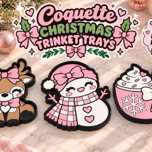 May include: Three black-rimmed trinket trays featuring a brown reindeer with a pink bow, a white snowman with a pink plaid scarf and hat, and a pink mug with whipped cream and a candy cane. Text reads Coquette Christmas Trinket Trays.