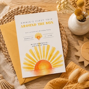 May include: A rectangular birthday party invitation card featuring a watercolor sun illustration and the text EMMIE'S FIRST TRIP AROUND THE SUN, JOIN US EMMIE'S BIRTHDAY PARTY, MARCH 27, 2-4 PM, AT 123 ANYWHERE ST., ANY CITY, ST 12345, tucked into a mustard envelope.
