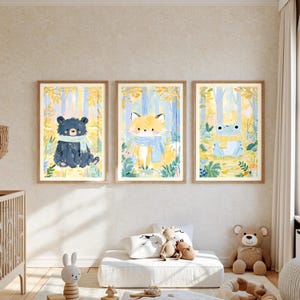 Peut inclure: Trois cadres muraux illustr&eacute;s avec des dessins &agrave; l'aquarelle repr&eacute;sentant un ours noir portant une &eacute;charpe bleu clair, un renard avec une &eacute;charpe bleu clair et une grenouille avec une &eacute;charpe jaune, sur un fond de for&ecirc;t jaune et bleu.