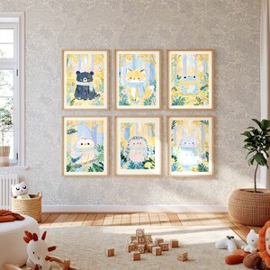 Peut inclure: Six impressions d'art rectangulaires dans des cadres en bois clair, chacune repr&eacute;sentant un animal diff&eacute;rent&mdash;un ours, un renard, une grenouille, un hibou, un h&eacute;risson et un lapin&mdash;portant une &eacute;charpe bleue dans une for&ecirc;t jaune et bleue.