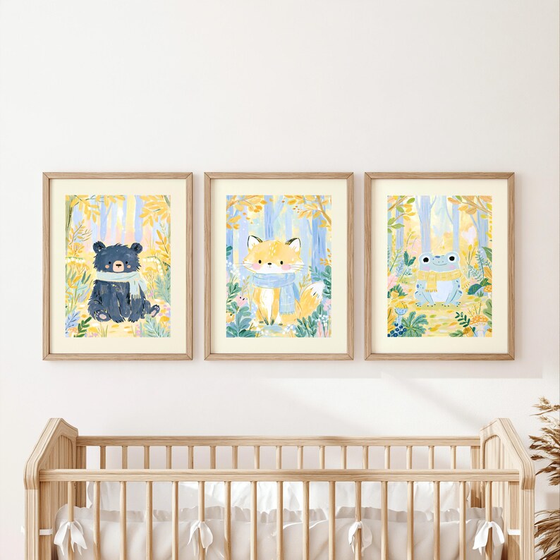 Peut inclure: Trois cadres muraux illustr&eacute;s repr&eacute;sentant un ours noir avec une &eacute;charpe bleu clair, un renard orange avec une &eacute;charpe bleu clair et une grenouille vert clair avec une &eacute;charpe jaune, sur un fond de feuillage forestier jaune et bleu.
