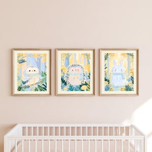 Peut inclure: Trois cadres muraux illustrant un hibou, un h&eacute;risson et un lapin bleu clair, portant chacun une &eacute;charpe bleu clair. Les animaux sont repr&eacute;sent&eacute;s sur un fond de feuillage et d'arbres aux tons jaunes et bleus.