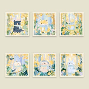Peut inclure: Un ensemble de six impressions d'art carr&eacute;es illustrant un ours noir, un renard, une grenouille, un hibou, un h&eacute;risson et un lapin. Chaque animal est repr&eacute;sent&eacute; dans une for&ecirc;t au feuillage automnal jaune, portant une &eacute;charpe bleue ou jaune.