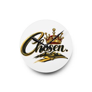 May include: A round wall clock with a white face featuring the word Chosen in black and gold script. Above the text is a gold crown with red accents and small white gems. Below the text is a stylized gold path leading toward black mountains.