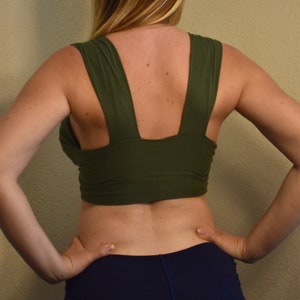 May include: A green crop top with a V-shaped back and a wide, adjustable strap. The top is made of a soft, stretchy fabric and is perfect for layering.