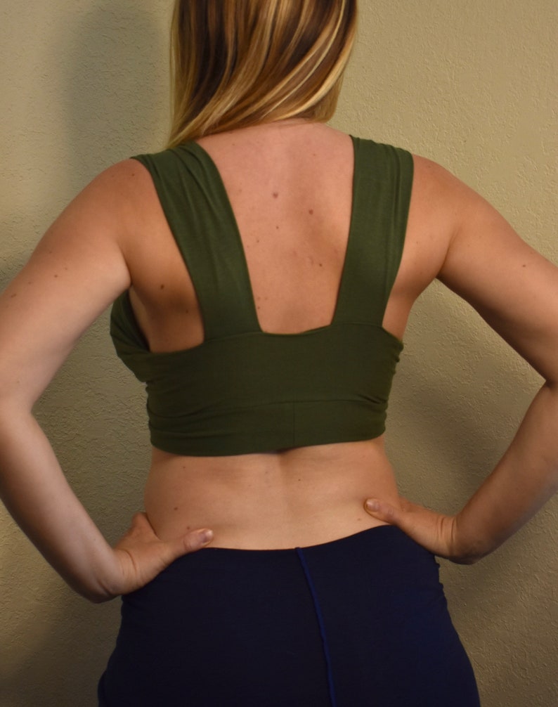 May include: A green crop top with a V-shaped back and a wide, adjustable strap. The top is made of a soft, stretchy fabric and is perfect for layering.