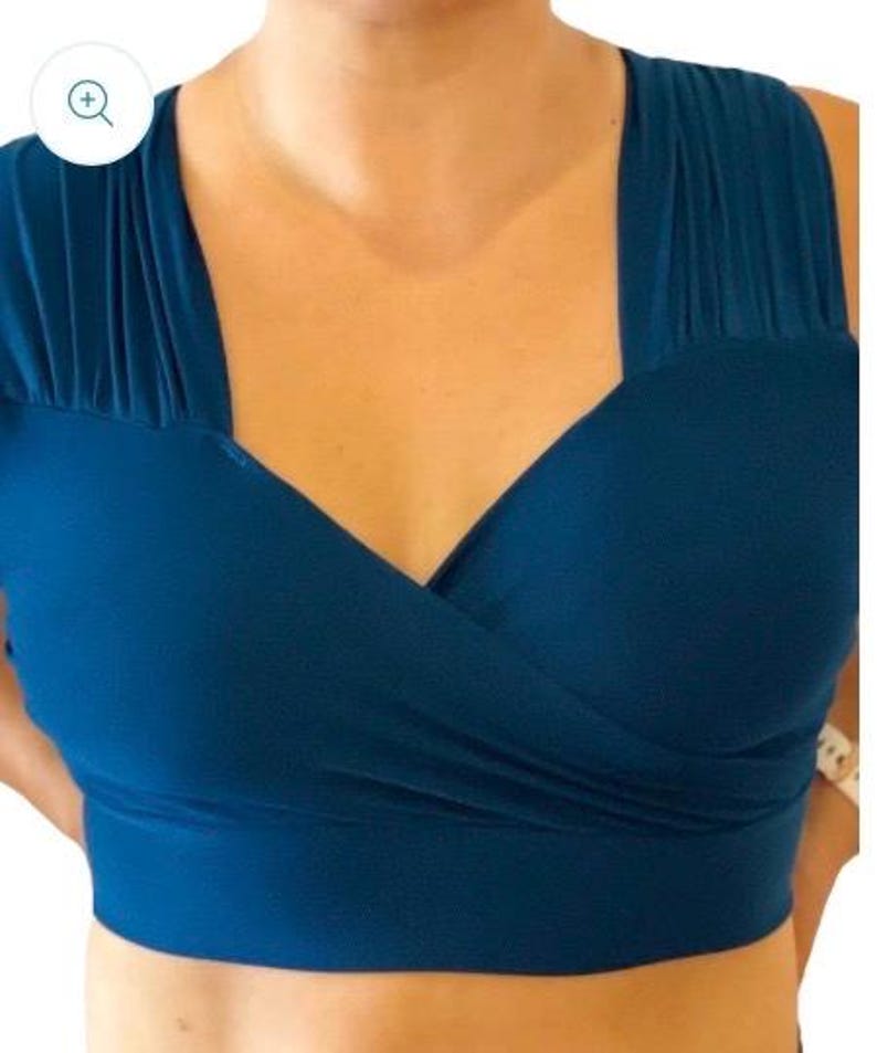 May include: A teal blue crop top with a deep V-neck and a criss-cross design in the front.
