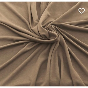 May include: A close-up shot of a fabric with a swirling pattern. The fabric is a solid, muted brown color. The material appears soft and drapes in folds, creating shadows and highlights.