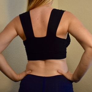 May include: A black sports bra with a V-shaped back and a navy blue pair of shorts.