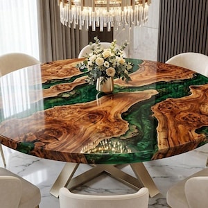 Op de afbeelding: Een ronde eettafel met een natuurlijk houten blad met een glanzende afwerking en een groene harsinleg, ondersteund door een metalen kruisvoet. De tafel is omringd door acht crèmekleurige gestoffeerde stoelen met gebogen rugleuningen.