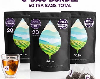 May include: A 3-bag bundle of PiPi Tea totaling 60 tea bags. Each black pouch features a leaf-shaped graphic of green terraced hills and mountains. The text reads 3-BAG BUNDLE, 60 TEA BAGS TOTAL, USDA ORGANIC, and PREMIUM WHOLE-LEAF OOLONG TEA.