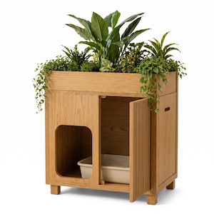 Puede incluir: Un mueble de madera marrón claro con una jardinera en la parte superior llena de varias plantas verdes. El mueble cuenta con una abertura rectangular en el lado izquierdo y una puerta de listones verticales a la derecha, revelando una bandeja beige.