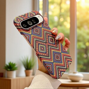 May include: A smartphone case featuring a repeating geometric pattern of diamonds and zigzags in shades of red, yellow, blue, and black. The case has a cutout for a horizontal camera module and is designed to fit a device with a specific camera layout.