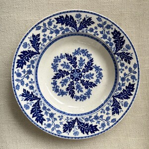 May include: A white ceramic soup bowl with a blue and white floral pattern. The bowl has a wide rim and a deep well.