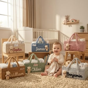 Peut inclure: Six paniers de rangement rectangulaires en feutrine beige, bleu, rose, marron, vert et gris, chacun portant un prénom brodé sur le devant et un petit ours en peluche attaché à la poignée. Les paniers contiennent divers articles pour bébé.