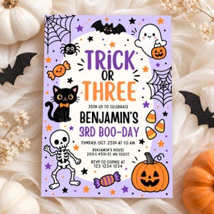 May include: A rectangular Halloween party invitation card with a light purple background featuring cartoon illustrations of a black cat, a skeleton, a ghost, a pumpkin, spiderwebs, bats, and candy. The text reads Trick or Three, Benjamin's 3rd Boo-Day, Sunday Oct 25th at 10 AM, Benjamin's house 200 E 45th St NY 10017, RSVP to Sophie at 123 1234 1234.