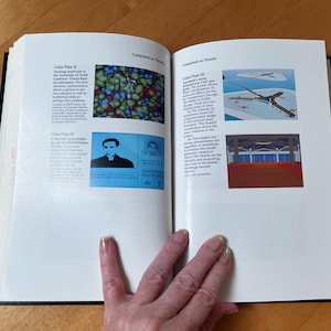 May include: An open hardcover book titled Computers as Theatre with white pages featuring black text and four color plates. The plates display a molecular model, a digital character, an architectural CAD design, and an interior building structure.