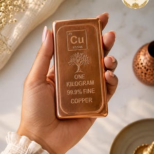 May include: A rectangular copper bar weighing one kilogram, featuring the chemical symbol Cu, atomic number 29, and atomic weight 63.546. The surface is engraved with a tree illustration and the text 99.9% FINE COPPER, showcasing a polished finish.