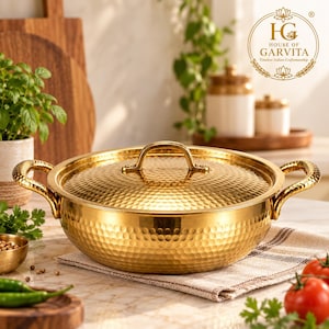 May include: A round, gold-coloured hammered metal cooking pot with a matching lid and two side handles. The pot features a textured, dimpled surface throughout the exterior and lid, with a polished metallic finish that reflects light.