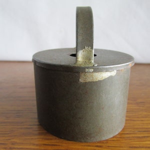 May include: A vintage metal cookie cutter with a handle. The cutter is green with some rust and has a worn, aged look.