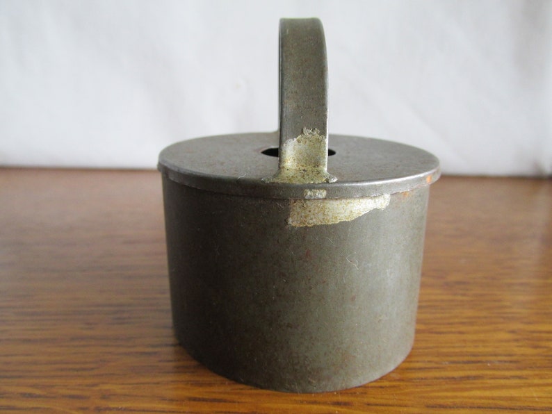 May include: A vintage metal cookie cutter with a handle. The cutter is green with some rust and has a worn, aged look.