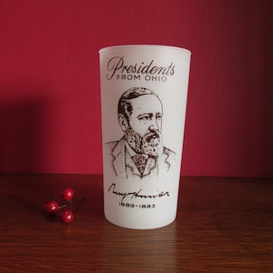 May include: White frosted glass with a black and white image of President Benjamin Harrison. The glass has the text "Presidents From Ohio" and "1889-1893" printed on it.