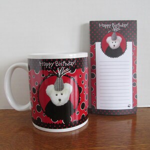 May include: A white ceramic mug and notepad set with a birthday theme. The mug features a white teddy bear wearing a party hat, set against a red background with black polka dots. The notepad has a matching design and the words "Happy Birthday!"
