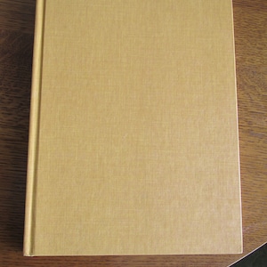 May include: A tan hardback book with a textured cover.